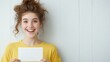© Lion - Smiling young caucasian female holding blank card against light background