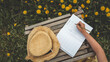 © shine.graphics - Close-up of a hand writing a spring to-do list in a lined notebook, with a background of blooming yellow dandelions and rustic wooden bench. Seasonal planning in nature