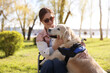 © New Africa - Woman in wheelchair hugging her service dog at park