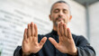 © surachet - leadership development A man with outstretched hands appears to be meditating or performing a calming gesture.