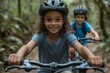 © EpochXstudio - Young siblings of different races riding bicycles side side down a forest path childhood equality