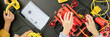 © Seventyfour - Website header shot of children building robotic gadget using various engineering tools and components on black table with tablet and wires. Hands of children controlling different parts of robot