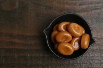 Wall Mural - tasty sweet caramel candies on wooden table, top view. space for text