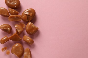 Wall Mural - many tasty caramel candies on light pink background, flat lay. space for text