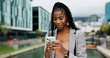 © peopleimages.com - Happy, phone and business black woman in city online for morning commute, travel and journey to office. Typing, corporate and person on smartphone for networking, connection and internet in town