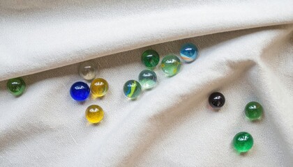 Poster - Colorful glass marbles displayed on soft fabric artistic composition home setting close-up view creative concept