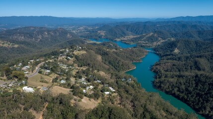 Poster - A tranquil scene captures a winding turquoise river cutting through vibrant greenery in a peaceful valley, with misty clouds drifting above the hills