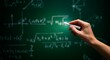 © Steffani - Hand holding chalk writing mathematics equation on green chalkboard