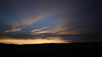 Wall Mural - Time lapse of late evening sky with colorful clouds drifting above rolling hills