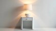 © Orislava - A minimalist white nightstand with a soft-lit lamp, creating a serene ambiance.