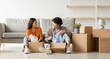 © Prostock-studio - Relocation day concept. Cheerful millennial Asian couple unpacking belongings and having conversation, moving to new apartment or their own house, copy space. Panorama