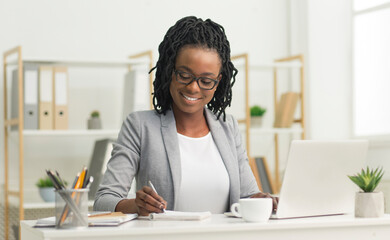 Aufkleber - Smiling Black Office Girl Sitting At Laptop Taking Notes At Work Indoor. Business Schedule Concept. Free Space