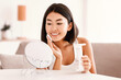 © Prostock-studio - Skincare Concept. Asian Woman Cleaning Face With White Pad Looking In Mirror. Beautiful Lady Removing Makeup With White Cosmetic Cotton Pad. Happy Smiling Female Taking Off Make Up From Facial Skin