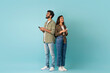 © Prostock-studio - Dating mobile app concept. Stylish young eastern man and woman hipsters standing back to back, using smartphones on colorful studio background, chatting online, looking at copy space, full length