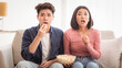 © Prostock-studio - Amazed Japanese Couple Watching Movie On TV Eating Popcorn On Weekend, Sitting On Sofa In Living Room At Home. Asian Family Watches Scary Film On Television Concept