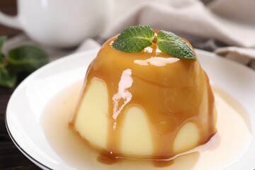 Wall Mural - delicious pudding with caramel sauce and mint on table, closeup