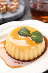 Wall Mural - delicious pudding with caramel sauce and mint on table, closeup