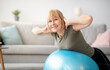 © Prostock-studio - Smiling senior woman doing exercises with fitness ball at home, space for text. Mature Caucasian lady working out her back muscles, training with sports equipment during coronavirus lockdown