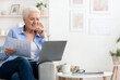 © Prostock-studio - Home office. Confident senior business woman working with laptop and papers in living room, free space