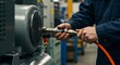 © NeedMoreMars - Close-up of a male technician's hands meticulously connecting an orange pneumatic air hose to an industrial compressor unit in a manufacturing workshop.