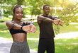 © Prostock-studio - Healthy Lifestyle Concept. Black millennial couple doing sport outdoors together, stretching arm muscles before training in summer park, free space