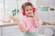 © Pixel-Shot - Cute girl with headphones listening to music in kitchen