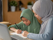 © Wanwajee - Happy family learning together. A mother lovingly supports her daughter during a study session. The girl uses a laptop and writes notes while the mother sits beside her, encouraging and engaged.
