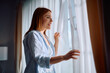© Drazen - Happy woman enjoying in view from her window in morning.