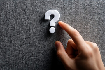 Poster - White question mark on gray textured background, finger pointing at it, symbolizing inquiry, question, problem solving, or decision making