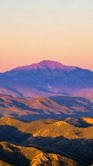 Poster - Golden hour sunlight bathes a majestic mountain peak, casting long shadows across the rolling hills and valleys below, creating a breathtaking panorama of nature's beauty