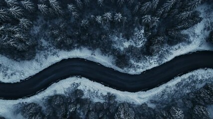 Poster - Aerial view of a winding road cutting through a snow covered forest in winter, creating a visually striking contrast between the dark asphalt and the white landscape