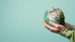 © siripimon2525 - Hands Holding a Sustainable Earth Globe on a Mint Green Background