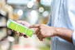 © Liubomir - A man in a blue shirt is holding a green box and pointing at the details printed on it while shopping.