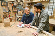 © Robert Kneschke - Experienced mentor teaching apprentice woodworking skills in workshop