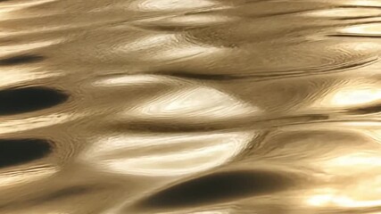 Poster - Golden ripples on the surface of water reflecting light at sunset creating a serene atmosphere