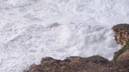 Wall Mural - powerful white foamy waves violently crashing against rocky portuguese shoreline, showcasing intense