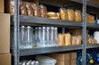 © DragonImages - Shelves filled with packaged food and bottled water in a storage area. Supplies neatly organized on metal racks with various items including pasta and snacks