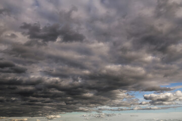 Wall Mural - Epic Dramatic storm dark grey cumulus rain clouds against blue sky background texture, thunderstorm