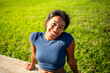 © mimagephotos - cheerful portrait of a young woman sitting outdoors by green field