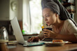 © Marko Geber - Worried young caucasian woman with a skincare facial mask using a laptop while having breakfast in the morning