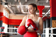 © New Africa - Woman putting on protective boxing gloves in training center