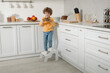 © New Africa - Little boy with cookies standing on step stool in kitchen