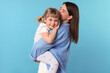 © New Africa - Happy mother and her cute daughter on light blue background
