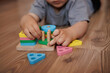 © Тетяна Кривоус - Close-up of child's hands playing with wooden educational toy-sorter. Horizontal photo. Concept of learning through play, fine motor skills and early childhood development