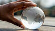 © BoOm - Hand gently holds clear globe featuring outline of Africa, symbolizing global awareness and connection. serene background
