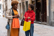 © Ceballos - Two smiling women showing shopping bags in the street