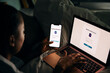 © Maskot - High angle view of woman accessing laptop through smart phone with authentication password while sitting in bedroom at h