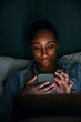© Maskot - Woman using smart phone in bedroom at night