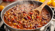 © AI_Vision - A steaming pot of homemade chili simmering on a cozy kitchen stove with a wooden spoon stirring away