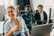© Maskot - Happy male and female computer programmers sitting on chair while looking away in office